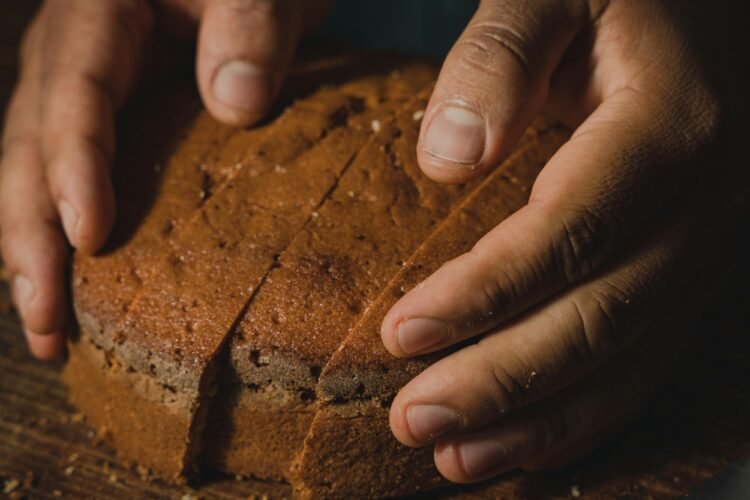 Hands gently holding a loaf of artisan bread on a wooden board in a cozy, rustic setting.